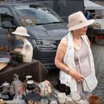 Elegant Woman Browsing Antiques at Outdoor Flea Market Elegant elderly woman shopping antiques at outdoor flea market with vintage collectibles on display.