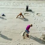Sunny Beach Day With Friends and Footprints People enjoying a sunny beach day with sand, footprints, and colorful swimwear.