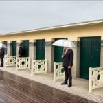 Seaside Memorial Ceremony by Vintage Beach Huts Memorial ceremony by seaside changing huts with umbrellas on rainy boardwalk.