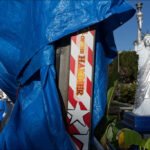 Carnival Scene With Statue of Liberty and Blue Tarp Colorful amusement park scene with blue tarp, Statue of Liberty replica, carnival game, and mascot.