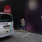 Young Boy by Police Van and Coca-Cola Ad in City Young boy standing near police van with Coca-Cola advertisement in urban city street.