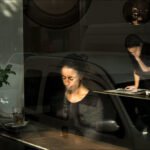 Contemplative Woman by Cafe Window With Coffee and Sunlight Woman sitting in cozy cafe by window with coffee, sunlight, reflections, and plant.