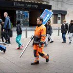 Traffic Worker Holding One-Way Sign in Antwerp City Center Construction worker holding one-way street sign in busy Antwerp city center.