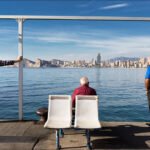 Elderly Friends Relaxing by Waterfront City Skyline Elderly men relaxing by waterfront with city skyline and ocean view.