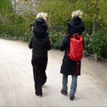Family Stroll on Nature Trail With Child and Backpack Family walking on nature trail with child on shoulders and red backpack.