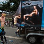 Summer Festival Fun With Stilt Walker and Neon Vibes Summer festival crowd with stilt walker, neon sunglasses, and KAV Bodywear advertisement.