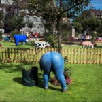 Whimsical Garden With Colorful Cow Sculptures and Playful Figure Colorful cow sculptures and humorous jeans figure in whimsical European garden.