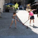 Girls Sweeping Cobblestone Street on a Sunny Day Two girls cleaning a cobblestone street.