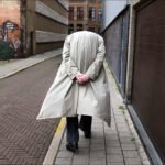 Mysterious Headless Figure in Trench Coat Walking Alley Headless figure in beige trench coat walking through mysterious urban graffiti alley.