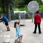 Children Exploring Interactive Park With Optical Spiral Exhibit Children exploring interactive park exhibit with optical spiral and educational displays.
