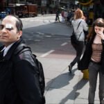 Injured Man Standing Strong in Busy City Street Injured man with eye bandage standing in busy urban city street.