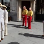 Men in White Suits and Colorful Costumes on City Street Men in white suits and yellow costumes standing on city street.