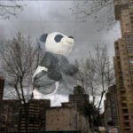 Plush Panda Reflected Against Urban Cityscape Plush panda toy reflected in cityscape with buildings and trees.