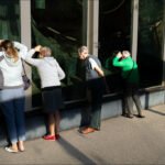 Zoo Visitors Watching Animals Through Glass Enclosure Visitors watching animals through zoo glass enclosure on a sunny day.