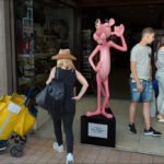 Pink Panther Statue at Lively Souvenir Shopfront Pink Panther statue outside souvenir shop with tourists shopping and exploring street.