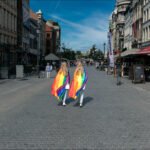 Colorful Pride Flags on Vibrant Cobblestone Street LGBTQ pride parade with rainbow flags on cobblestone street in vibrant urban city.