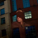 Urban Reflection Portrait on Brick and Glass Facade Urban building reflection with brick facade, windows, and silhouette of person in hat.