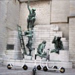 Electric Scooters Meet Historic Bronze Worker Statue Scooters near bronze worker sculptures.