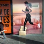 Urban Sport Store Mural with Running Woman and Pedestrian Sport store advertisement with running woman mural and man walking on urban street.