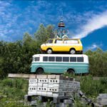 Whimsical Vintage Bus and Van Sculpture with Bicycles Whimsical stacked vintage bus and van sculpture with bicycles under a bright blue sky.