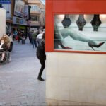 City Street Life With Pedestrians and Fashion Ad Busy city street with pedestrians, delivery truck, wheelchair user, and fashion advertisement in window.