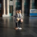 Women Talking at Modern Train Station Atrium Women talking inside busy train station with modern art and historic architecture.