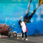 Playful Person Interacts With Colorful Underwater Mural Person playfully cleaning colorful underwater mural with fish and coral in vibrant street art scene.