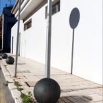 Minimalist Urban Design with Concrete Bollards and Shadows Minimalist urban street with concrete bollards, metal poles, shadows, and modern white wall background.