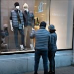 Couple Window Shopping Trendy Winter Fashion Jackets Couple window shopping winter puffer jackets at trendy urban fashion storefront.