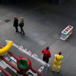 Colorful Fruit Sculptures in Vibrant Indoor Public Space Colorful fruit sculptures in modern indoor public space with people, security staff, and pigeon.