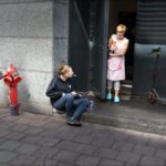 City Sidewalk Moment With Woman and Cat Woman sitting near fire hydrant.