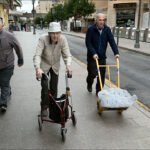 Everyday Life on a Busy City Street Urban street scene with three men walking, elderly man with walker, and delivery cart.