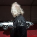 Man in Leather Jacket at Classic Car Show Man in leather jacket admiring classic silver sports car at vintage car show.