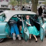 Glamorous Woman Posing With Teal Vintage Car at Show Woman in turquoise dress posing with teal vintage car at classic car show.