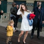 Woman in White Dress With Child in Yellow Raincoat Woman in white dress with child in yellow raincoat at outdoor event.