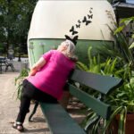 Woman Relaxing on Park Bench Beside Butterfly Sculpture Woman relaxing on green park bench beside artistic egg sculpture with butterfly design.