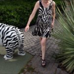 Woman in Zebra Print Dress Walking by Zebra Statue Woman in zebra print dress walking by zebra statue in garden walkway.