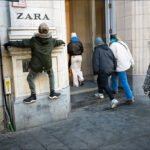 Boy Climbing Wall Outside Zara Store on Busy Shopping Day Boy climbing wall outside Zara store with fashionable women entering during city shopping day.