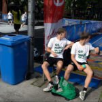 Youth basketball players resting on bench during outdoor community tournament game.