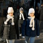 Children walking on a winter city street wearing warm jackets and hats.