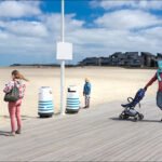 Family enjoying a peaceful beach day on a sunny boardwalk by the ocean.