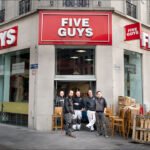 Five Guys restaurant team posing outside newly opened burger location.