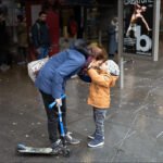 Mother and son sharing a joyful moment on a rainy city street.