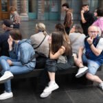 Visitors seated in modern museum hall reflecting and waiting during cultural exhibition.