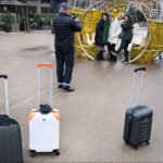 Women posing for a winter travel photo in a festive urban holiday setting.