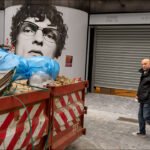 Urban street mural of young man beside dumpster and passerby symbolizing city renovation.