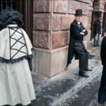 Elegant Victorian couple in vintage city street scene with historical architecture.