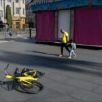 Yellow bicycle and father with child in vibrant urban street scene with colorful kiosk.
